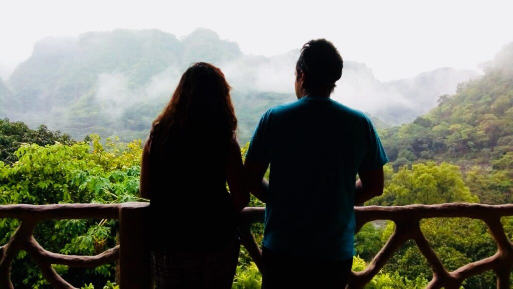 dos personas mirando el paisaje verde y frondoso de las montañas y río
